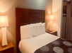 A white king bed with a wooden headboard and two night stands with lamps at the Oceanside Inn & Suites, a Days Inn by Wyndham.