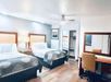 A hotel room with two queen beds, a night stand, a desk and chair with a mirror over it, art on the walls, and a closet with mirrored doors.