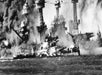 A black and white photo of the Pearl Harbor Attack in 1941 with lots of smoke in the air and ships in the water.