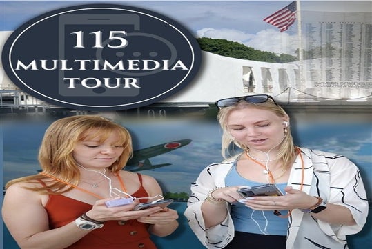 Two women holding smartphones and earbuds while on the USS Arizona Narrated Multimedia Tours with a poster behind them.