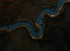 Aerial view of a winding river or stream cutting through a dark, textured landscape with brown and green vegetation edges.