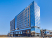 Modern high-rise hotel building with large glass windows, labeled "Omni Hotel," under a clear blue sky.