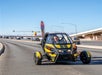 A woman driving a yellow GoCar on the highway on a sunny day with cars going the other way in the background in Las Vegas.
