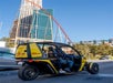 View of a yellow doorless GoCar with two people sitting in it stopped at a traffic light on the streets of Las Vegas.