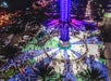 Aerial view of an illuminated amusement ride with crowds gathered around it at night.