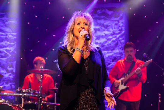 A woman dressed in black singing at the Ozarks Gospel show in Branson.