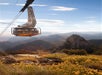 A tramcar in the air with mountains in the background and a blue cloudy sky overhead at Palm Springs Aerial Tramway.