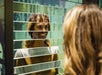 A visitor bewildered with a smile at their reflection in one of the museum’s optical installations.