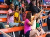 Fans sitting in the stands and cheering with their fists up at Paula Deen's Lumberjack Feud Supper Show.
