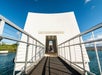 View of the USS Arizona Memorial entrance with railing and water visible under a clear blue sky.