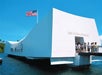 USS Arizona Memorial at Pearl Harbor with visitors entering, featuring a prominent American flag against a clear blue sky.