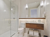 Single vanity with complimentary toiletries, fresh towels and a glass-enclosed shower inside a private bathroom.