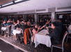 People are seated at tables inside a restaurant, raising their glasses in a toast.