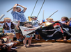 A group of children dressed as pirates stand on a ship deck, holding flags and foam swords, with some smiling and one child raising arms excitedly.