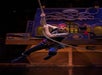 A performer dressed as a pirate swings on a rope in front of a pirate ship stage set decorated with a large skull and octopus design.