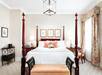 A four-poster king bed with a decorative teddy bear, a footboard bench, desk and chair, and more.