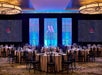 The banquet room at the Portland Marriott Downtown Waterfront with round cloth covered tables with black chair and soft romantic overhead lighting.