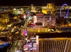 Aerial night view of the Las Vegas Strip showing brightly lit hotels, casinos, and the High Roller observation wheel.
