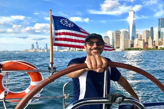 The captain at the wheel of a Private Sailboat Charter to the Statue of Liberty and NYC.
