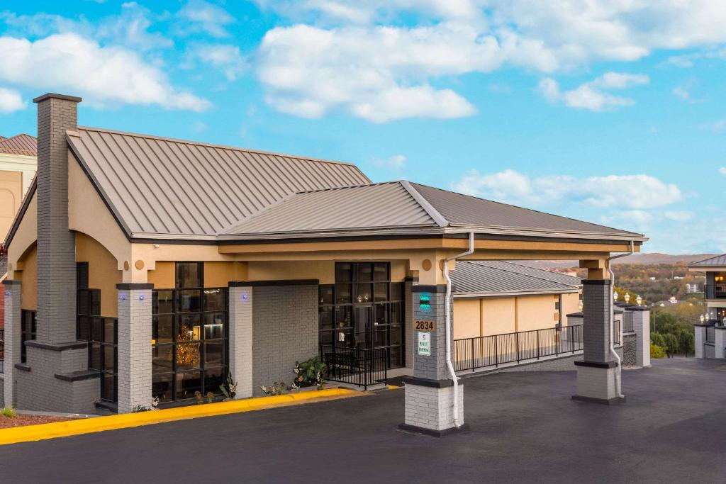 A modern building with a covered entrance and large glass windows under a blue sky with scattered clouds.