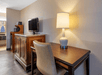 A flat screen TV, desk and chair, and a lamp inside a guest room at Quality Inn Kennedy Space Center, Florida.