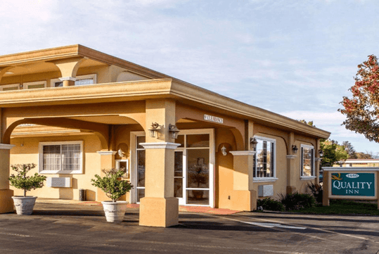 Exterior of the Quality Inn Ukiah with the sun shining on the front of the building.