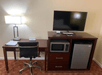 A work area with a desk, flat-screen TV, mini-fridge, microwave inside a guest room at Quality Inn Ukiah, CA.