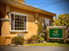 A small green and beige sign for the Quality Inn Ukiah next to a small landscaped area on a sunny day.