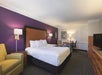 Guest room with a king bed, an armchair, desk and chair