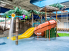 Indoor water park with slides, water features, and palm tree decorations.