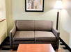 Gray patterned couch in a living room with a wooden coffee table, floor lamp, and abstract art on the wall.