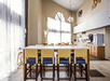 A dining area with tall tables with blue and yellow chairs, a small breakfast bar, and floor to ceiling windows.