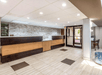 A long two toned wooden front desk with a stone wall behind it and glass entrance doors to its left at the Quality Inn at the Park.