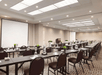 Meeting facility equipped with two white screen projector, tables and chairs.