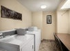 Washers and dryers and a table with two chairs inside a guest laundry room.