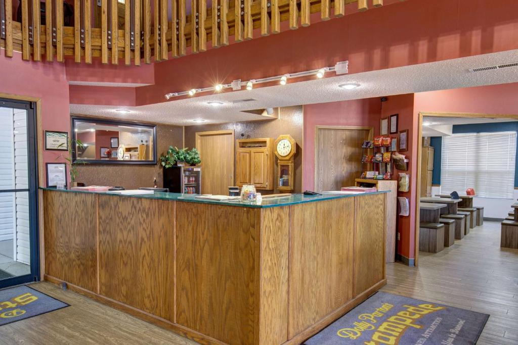 Hotel reception area with a wooden desk, brochures on the side, and a seating area in the background. Walls are painted red and feature wooden decor details.