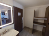 The bathroom features a sleek sink and a well-lit mirror, perfect for daily routines.