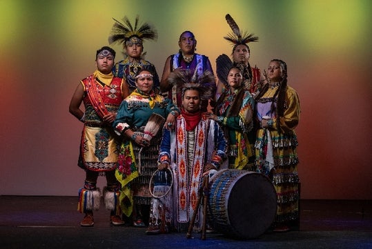 The cast of the Red Heritage Dinner Show in their costumes gathered together with their instruments on stage.