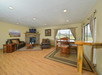 Spacious living room with wooden floors, stone fireplace, leather sofas, dining table, and large windows with scenic views.
