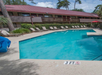 Outdoor pool area with lounge chairs and a building in the background. The pool is marked with a "3 FT" depth sign.