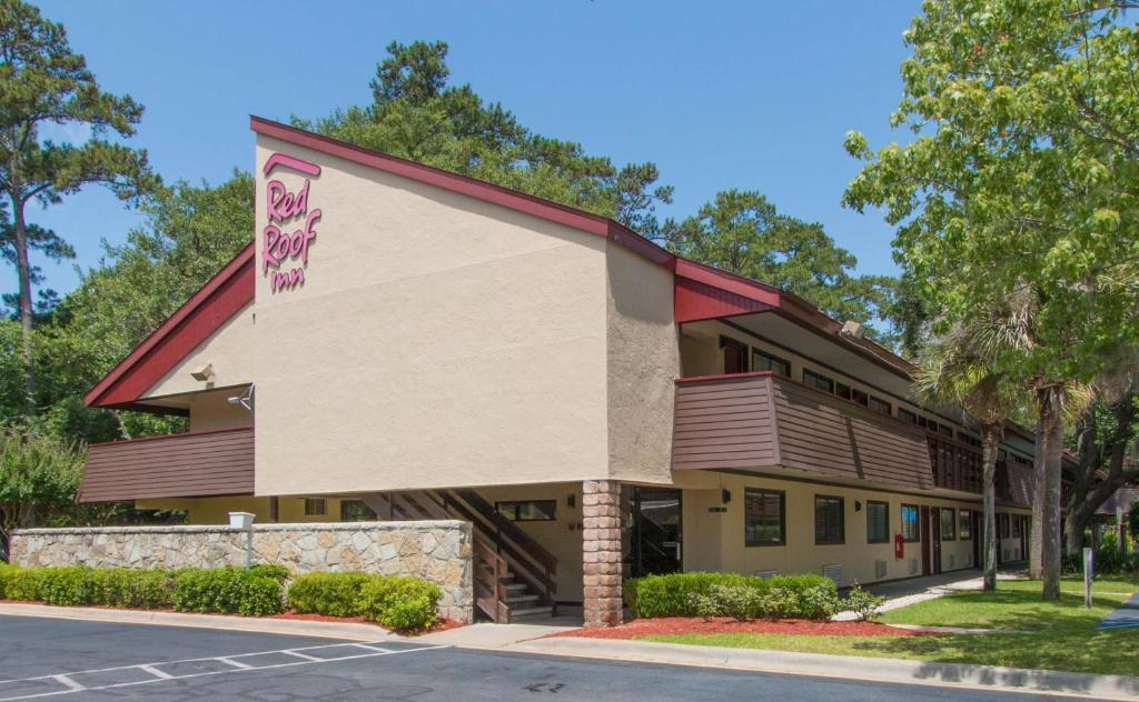 Two-story Red Roof Inn building with exterior corridors and a sign on the side, surrounded by trees.