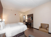One king bed, microwave, mini-refrigerator, flat-screen TV, desk, and a mini-sofa inside a guest room.