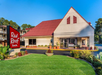 Exterior view of Red Roof Inn with a red-roofed building, manicured lawn, and a sign displaying the hotel name near the entrance.