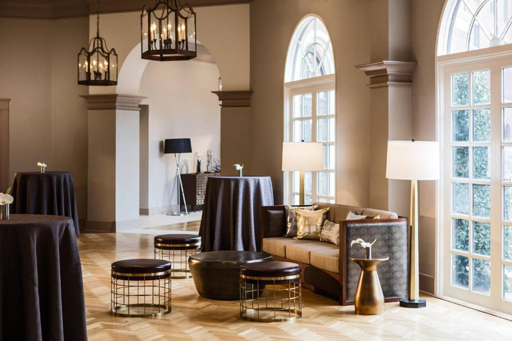 Elegant lounge area with a sofa, round tables, modern lighting fixtures, and large windows letting in natural light.