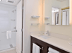 Single-vanity mirror, fresh towels and a glass-enclosed shower inside a private bathroom.