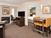 Separate living area with a fireplace, work desk, flat-screen TV and dining table.