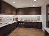 A breakfast area with dark brown top and bottom cabinets with white countertops lines with different breakfast foods.