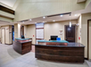 Modern hotel reception area with curved wooden desks, computers, and decorative paneling on the wall.