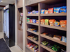 Shelves stocked with various snacks, including chips, candy, and crackers, alongside a refrigerator containing cold beverages.