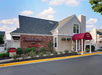 Exterior of a Residence Inn by Marriott, featuring a brick facade, pitched roof, and red canopy over the entrance. A "Check In" sign is visible on the left. Landscaping includes shrubs.